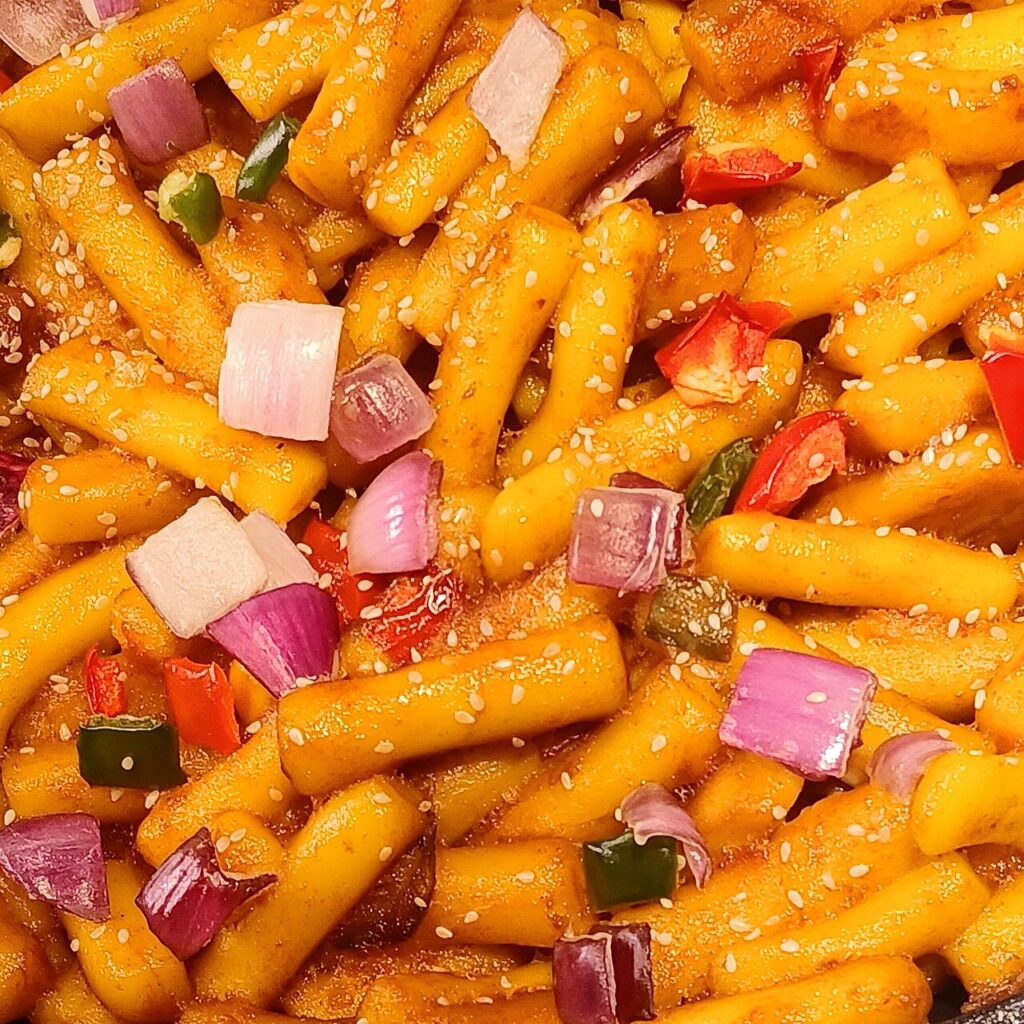 Đĩa tokbokki bánh gạo cay rắc mè cùng hành tây, ớt