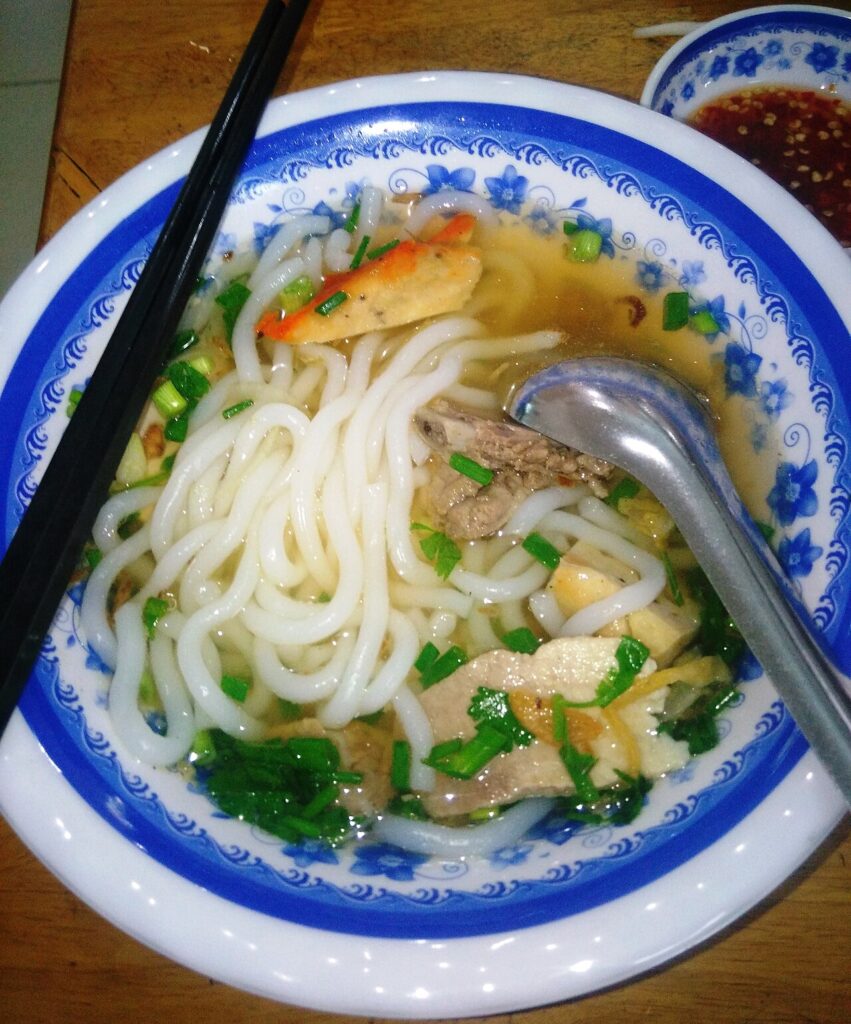 Sợi bánh canh bột gạo trắng mềm trong nước dùng trong, kèm chả cá và thịt