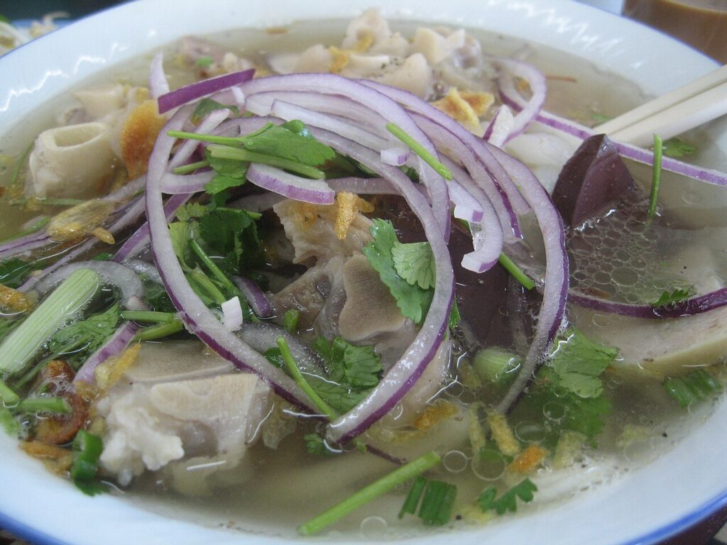 Tô bánh canh lòng thập cẩm với hành tím, rau mùi và nước dùng trong