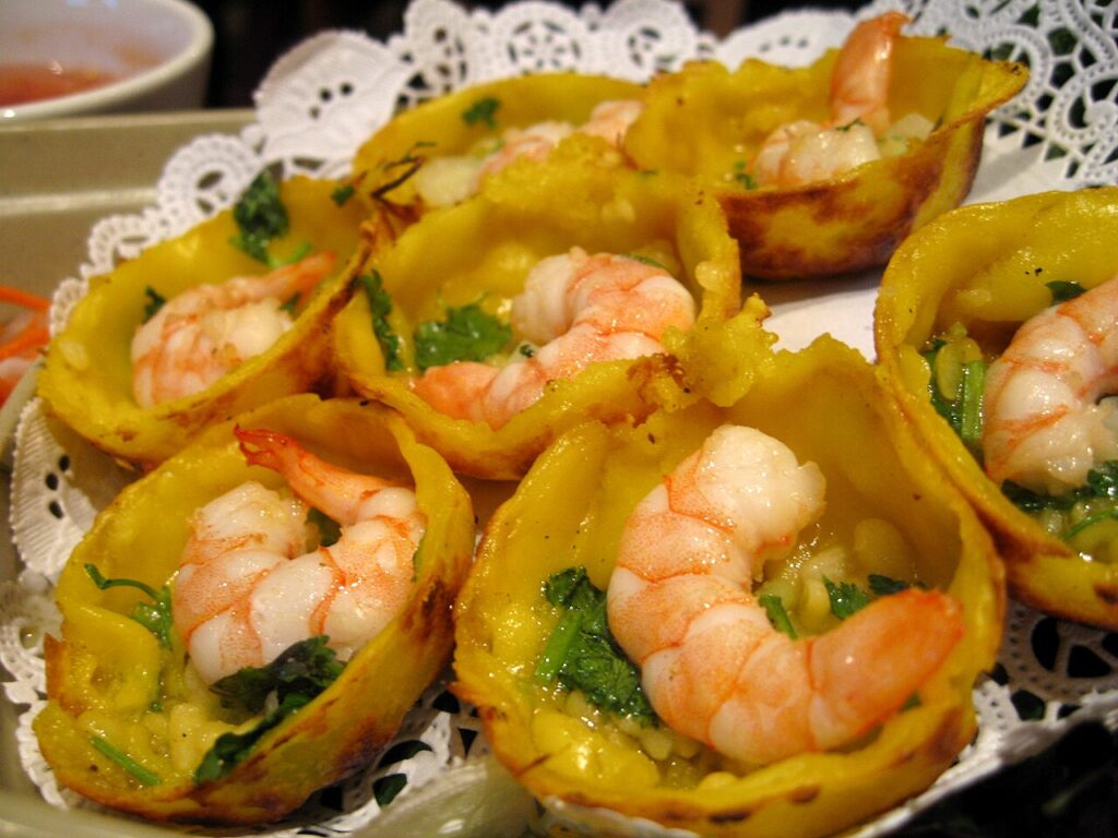 Bánh khọt tôm vàng giòn xếp trên đĩa, ăn kèm nước chấm