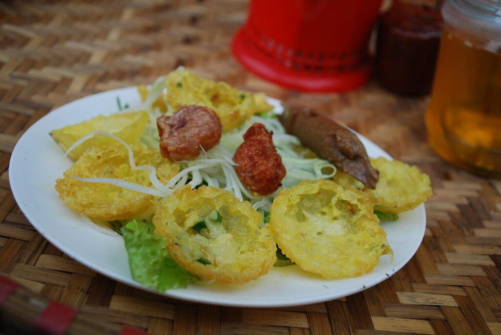 Đĩa bánh nhỏ chiên vàng ăn kèm xíu mại và rau