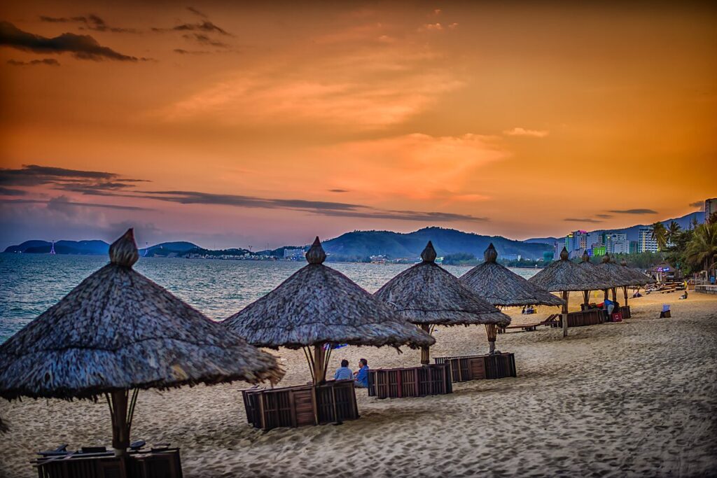 Quán cafe Nha Trang view biển với dãy dù lá trên bãi cát lúc hoàng hôn