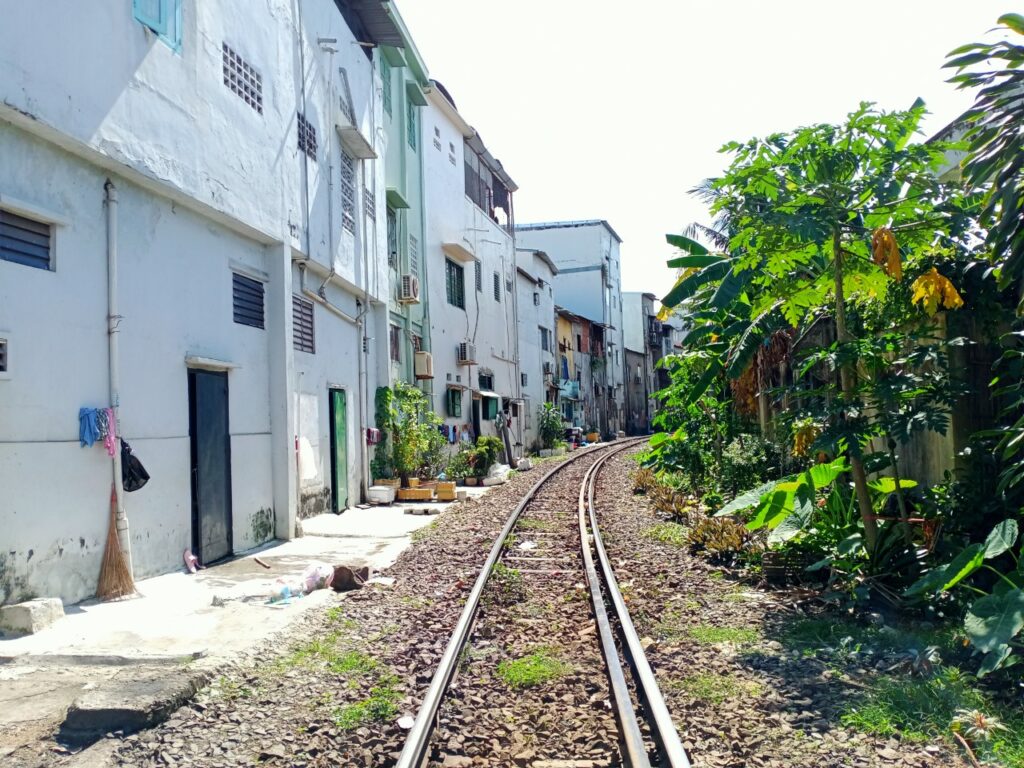 Đường ray xe lửa chạy giữa dãy nhà và cây xanh ở Nha Trang