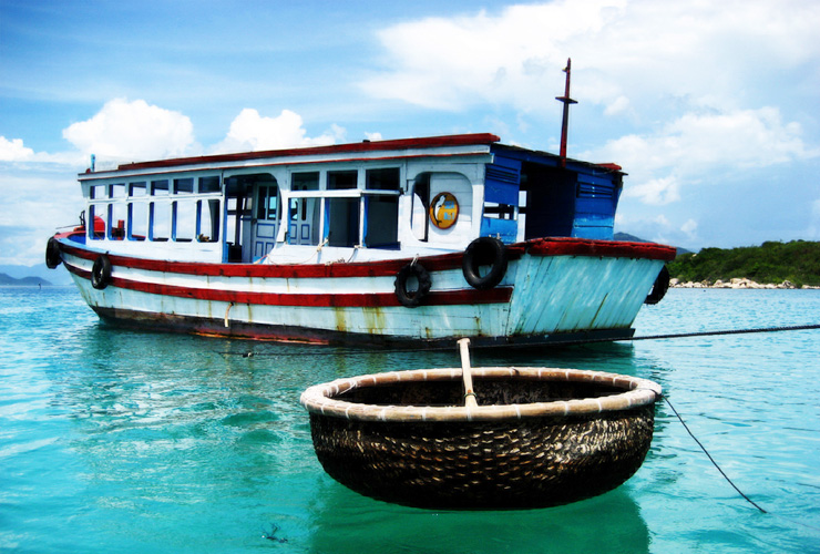 Chiếc thuyền thúng và tàu gỗ neo trên làn nước trong xanh quanh đảo Nha Trang