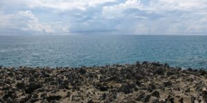 Ghềnh đá sẫm màu gồ ghề bên biển xanh, kiểu cảnh quan hoang sơ như ở Hang Heo Nha Trang