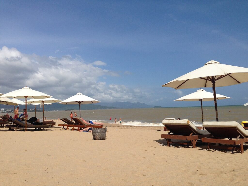 Hàng dù trắng và ghế nằm trên bãi cát gần các homestay Nha Trang gần biển