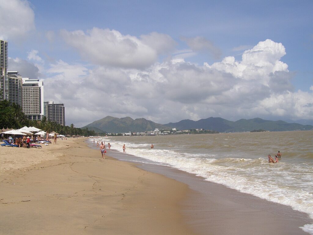 Bãi biển Nha Trang ngày nắng đẹp với mây trắng và dãy núi phía xa