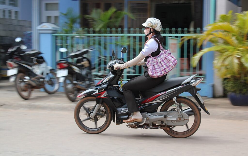 Người lái xe máy đội mũ bảo hiểm, mang găng tay, áo khoác chống nắng